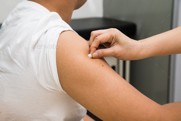 Medical doctor swap arm of patient with alcohol before vaccination - Stock Photo - Images