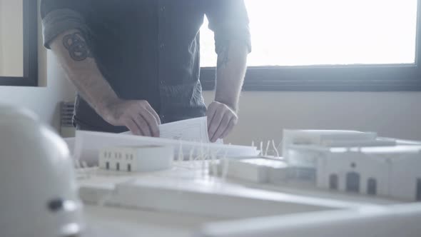 Architect looking at blueprint and architectural model