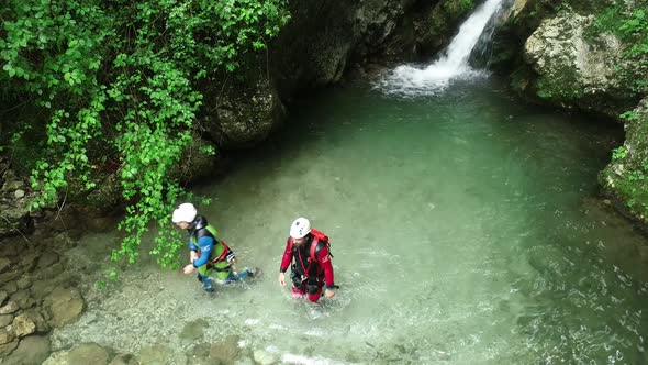 Aerial view of couple coming out of a waterfall at Soca river in Slovenia. alt