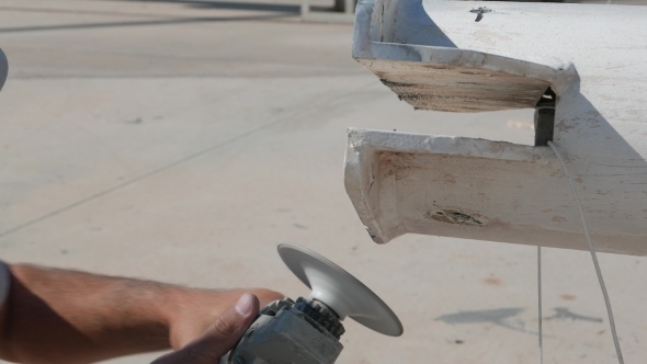 Worker Sanding Yachts Mast With Angle Grinder