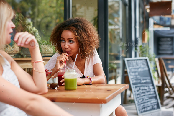Female friends meeting at sidewalk cafe - Stock Photo - Images