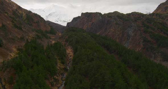 Aerial closeup profile of Troopers helicopter flying past glacier and black cliffs, drone