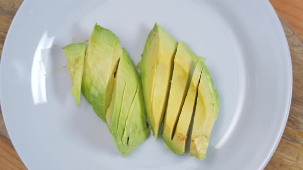 Sliced Avocado Halves On A White Plate Spinning 01