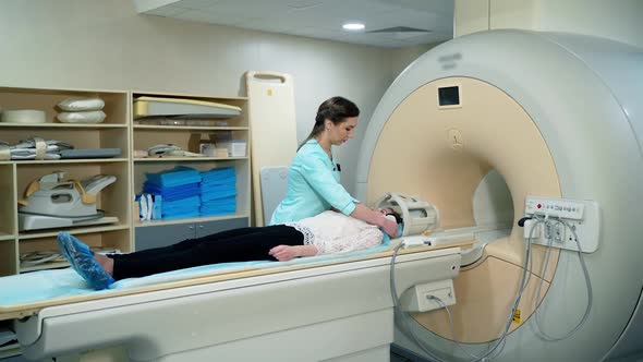 Medical scanning equipment and a female patient. Doctor preparing patient before the mri procedure.  alt