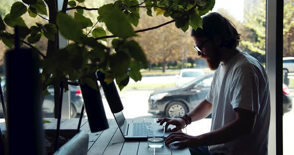 Man Working on Laptop in Cafe Window Silhouette