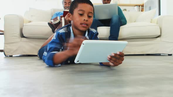 Boy using digital tablet in living room alt
