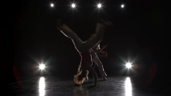 Two Woman Are Practicing Capoeira in Darkness Against Spotlight alt