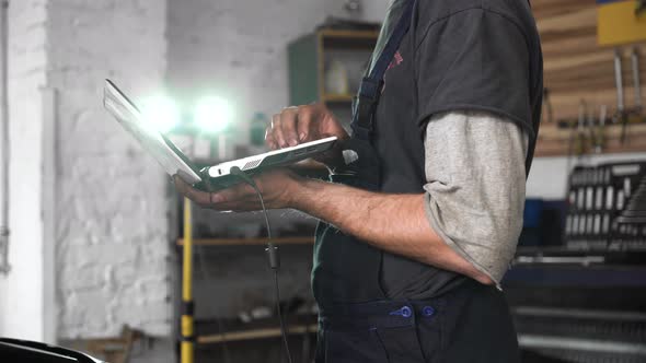 auto repairman diagnoses a car using a computer. car workshop. close-up alt