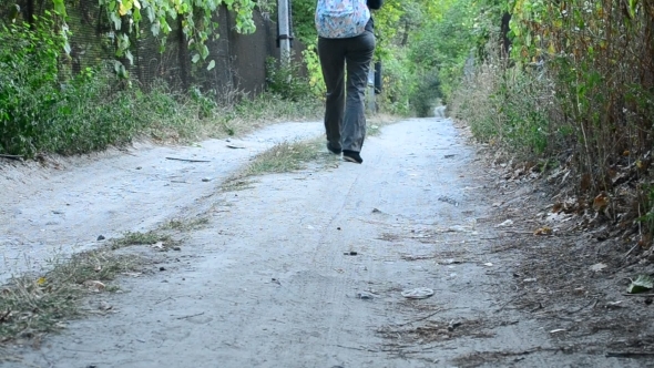 Woman In Trousers With Backpack Walks Away