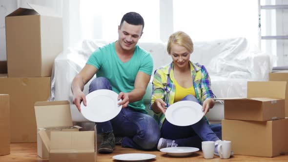 Smiling Couple Unpacking Boxes With Kitchenware 3 alt