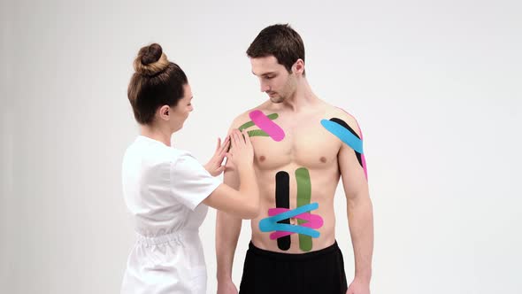 Shoulder treatment with kinesio tape. Physiotherapist applying elastic therapeutic tape alt