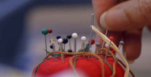 Woman Takes a Pin out of a Pin Cushion