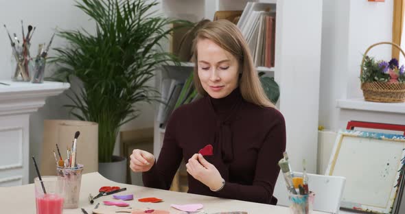 Young Woman Preparing Handmade Heart Cards for Valentine's Day Signing Them