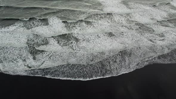 Drone Tilting Down Over White Surf On Black Sand Beach alt