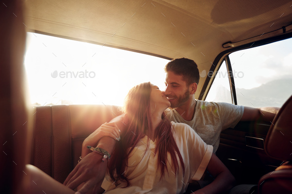 Beautiful couple kissing in back seat of a car