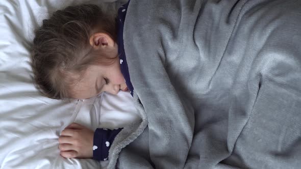 Authentic Cute Little Girl Sleeping Sweetly In Comfortable White and Grey Bed Middle Plan