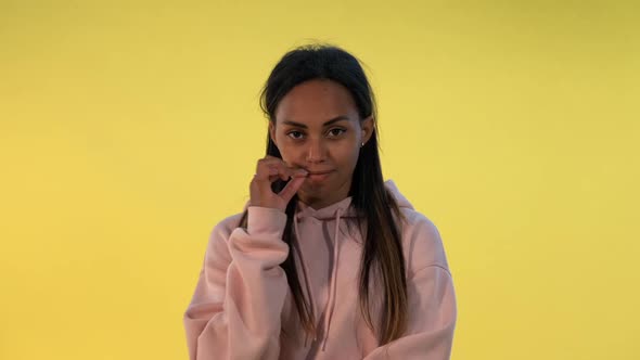 Portrait of African Woman's Lips Closing Zipper on Yellow Background alt