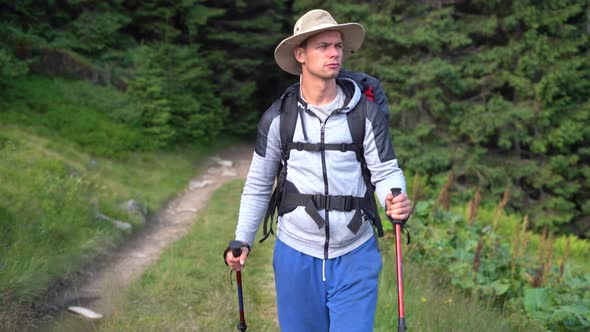 Portrait of Millennial Traveler Male Tourist with Trekking Sticks and Tourist Backpack Coming Out of alt
