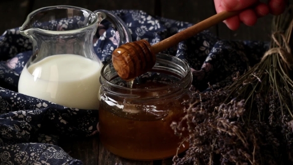 Open Glass Jar Of Liquid Honey With Honeycomb