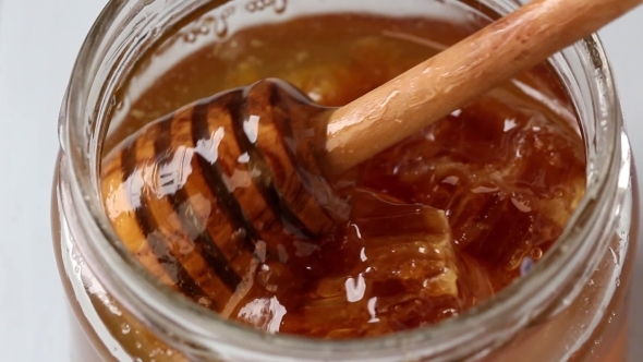 Open Glass Jar Of Liquid Honey With Honeycomb And