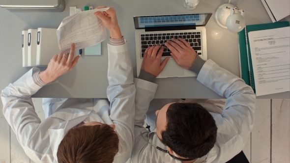 Two Doctors Discussing And Working Together alt