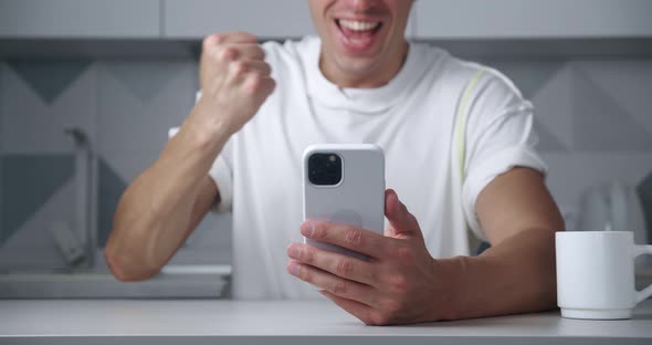 Closeup of a Happy Man Rejoicing at Winning on a Mobile Phone alt