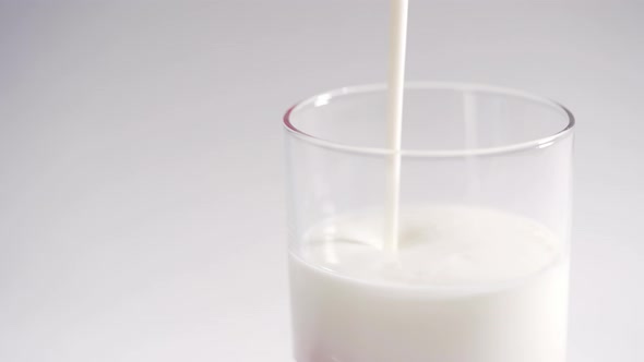 A Person Pours Fresh Organic Yogurt Into a Transparent Glass. Milk Yogurt Slowly Fills the Glass
