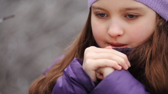 Child Warms Her Hands And Looks At Them In Winter