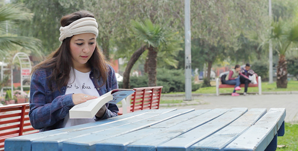 Beautiful Girl is Reading Book in the Park