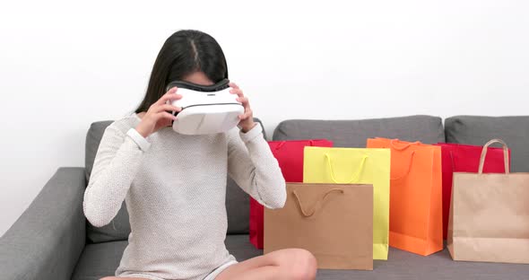 Woman using virtual reality device for shopping experience at home alt