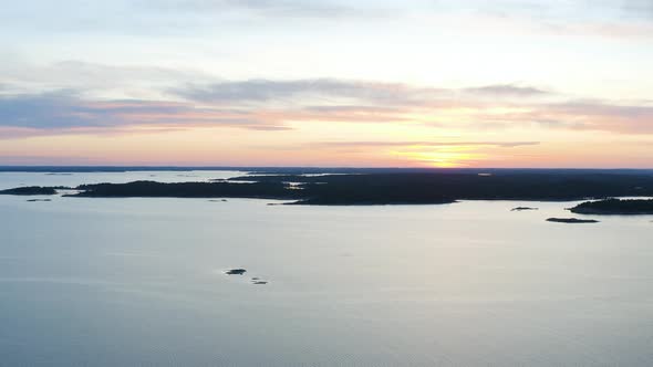 Aerial, rising, drone shot, tilting towards the silhouette coast of Porkkala, in the archipelago of alt