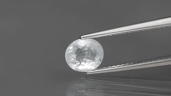 Natural Oval Aquamarine in the Tweezers on Background