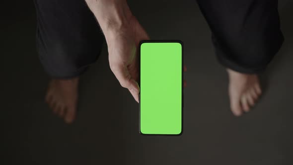 POV Top View Shot of Man Using Phone with Green Screen Indoor