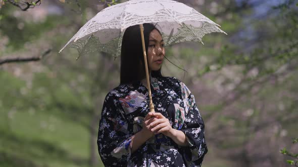 Portrait of Charming Asian Beautiful Young Woman Standing with White Sun Umbrella in Spring Park alt