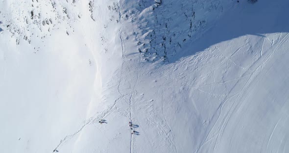 Overhead Aerial Top View Over Winter Snowy Mountain Ski Track Field with People in Sunny Day
