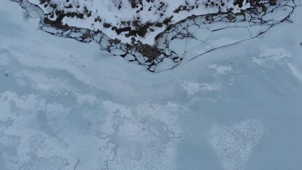 Frozen lake with breaked ice filmed from above