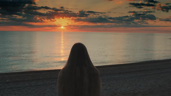 Woman Walking To the Sea and Raising Her Hands Up alt