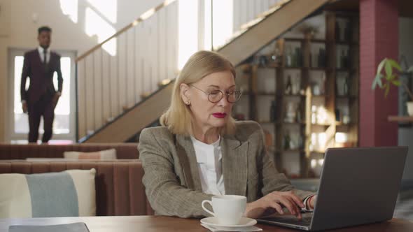 Senior Businesswoman Using Laptop in Restaurant alt