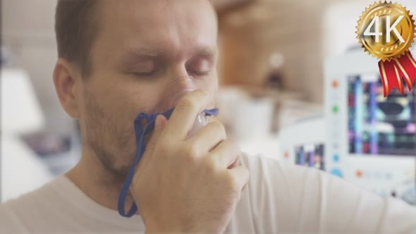 Young Man is Caughing Breathing Through Nebulizer alt
