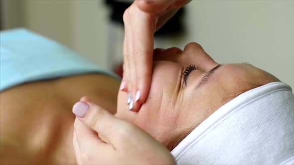Massage Therapist Cosmetologist Makes Cheeks Massage for Woman in Beauty Salon