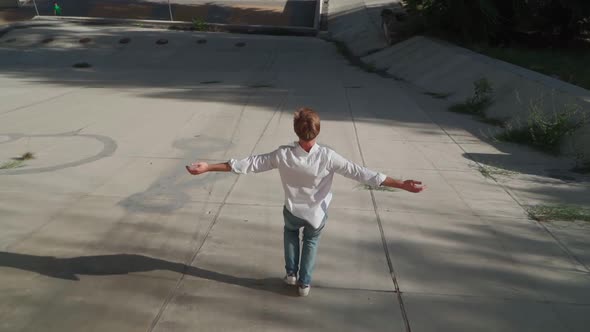 Happy Young Man raising hands to the sides runs down concrete slope Urban Park alt