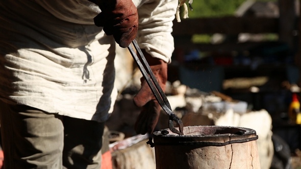 Blacksmith Forging Tongs Corrects the Crucible in the Furnace alt