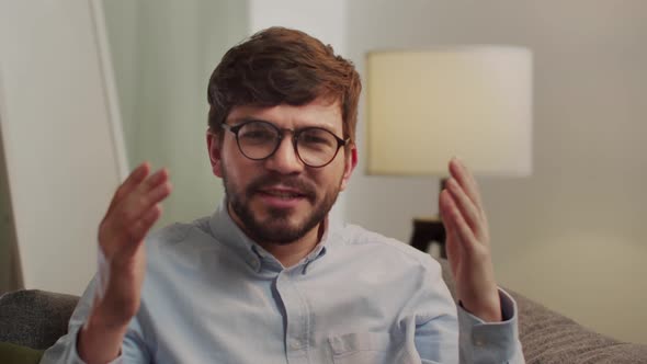 Aggressive Man Speaks to the Camera While Sitting in the Living Room alt