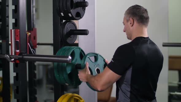 Handsome Strong Man Puts a Disk on the Barbell Turns to the Camera and Smiles  Slow Mo alt