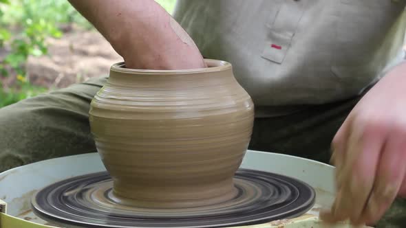 Male Makes a Clay Jug on a Rotating Circular Loom Outdoors on a Sunny Bright Day alt