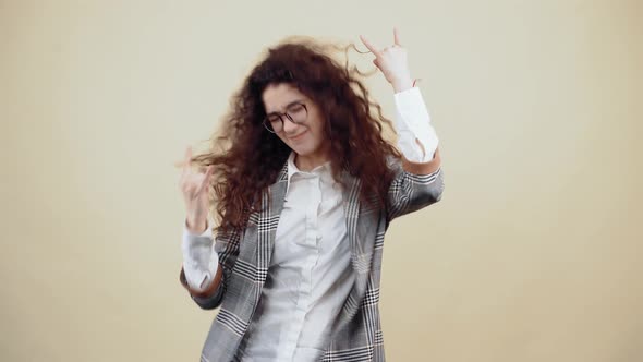 The Crazy Young Woman Dances Rock with Curly Hair in a Gray Jacket and White Shirt with Glasses alt