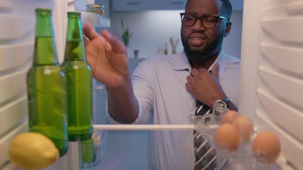 Tired businessman loosening tie, taking two bottles of beer after hard day