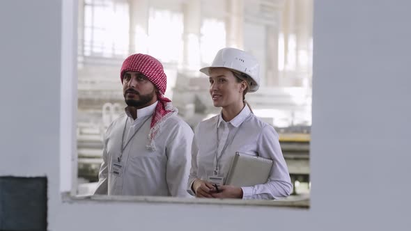 Multi-ethnic group of engineers discussing process of production at building