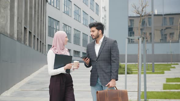 Muslim Businessman in Suit Showing Something on Smartphone to His Female alt