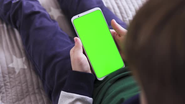 Smartphone in Hand with a Green Screen The Child Is Holding a for Keying Close-up Playing a Game